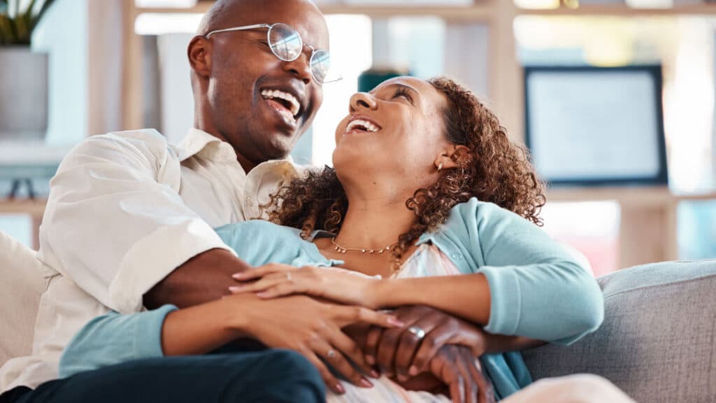 Smiling couple relaxing together on a couch, reflecting confidence, wellness, and a healthy lifestyle