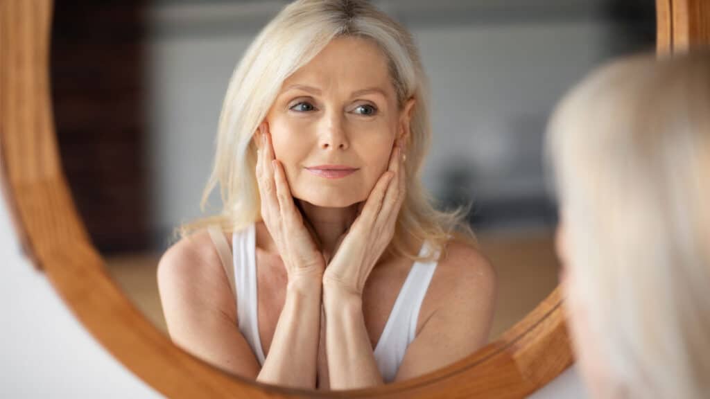 Woman checking her skin in the mirror after fluorouracil treatment