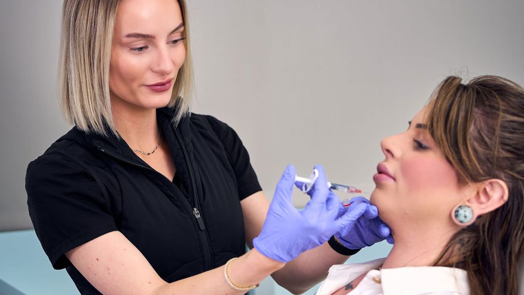 Woman receiving a lip filler treatment by an experienced dermatologist
